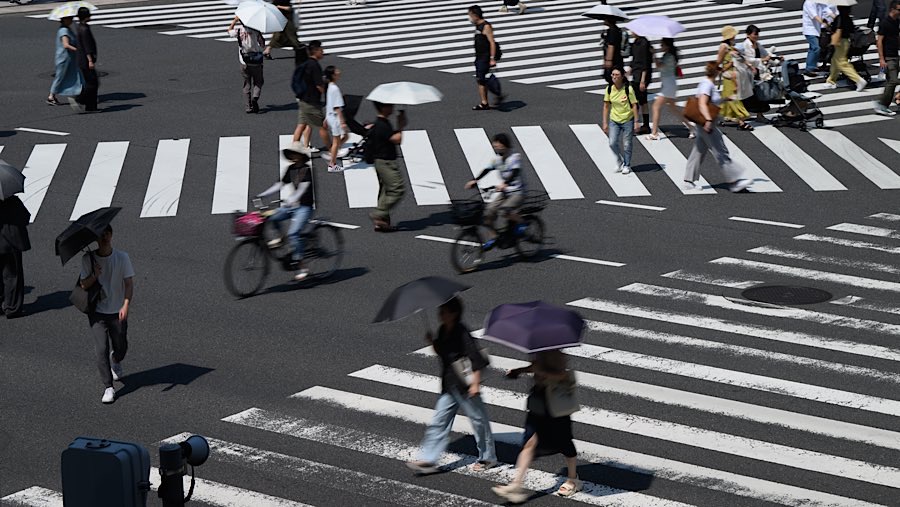 Pejalan kaki menyeberang jalan di distrik Ginza saat suhu tinggi melanda Tokyo, Jepang, Minggu (24/8/2025). (Akio Kon/Bloomberg)