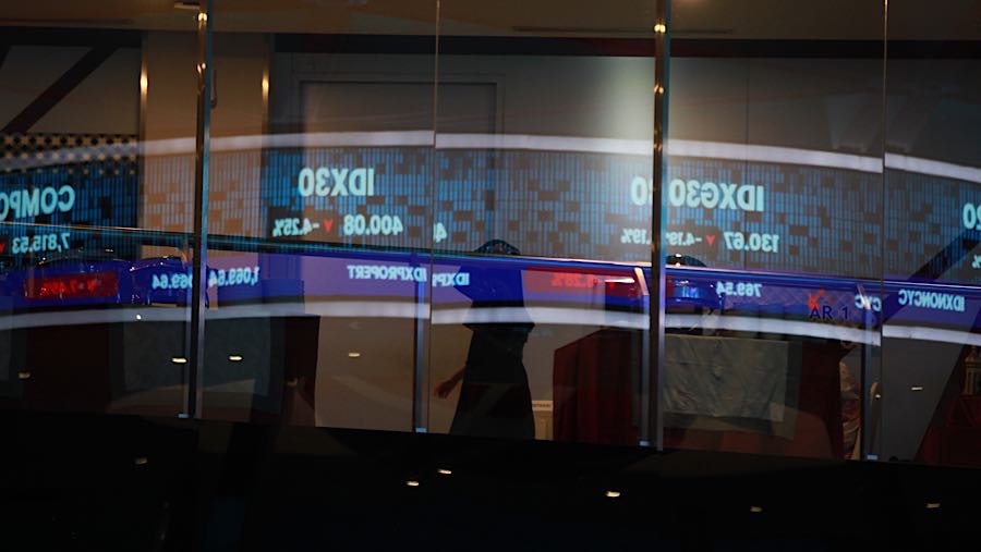 Karyawan melintas di depan layar pergerakan harga saham (IHSG) di Bursa Efek Indonesia (BEI), Kamis (29/1/2026). (Bloomberg Technoz/Andrean Kristianto