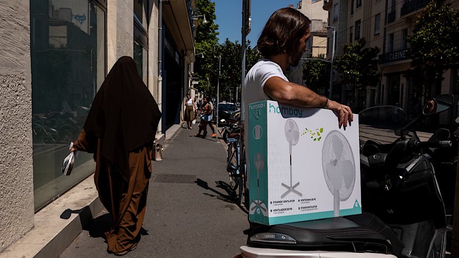 Warga memegang kotak kipas angin selama gelombang panas di Marseille, Prancis, Selasa (1/7/2025). (Jeremy Suyker/Bloomberg)